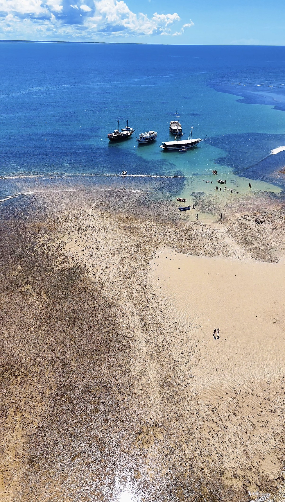 Barcos e piscinas naturais vistos do alto em Recife de Fora