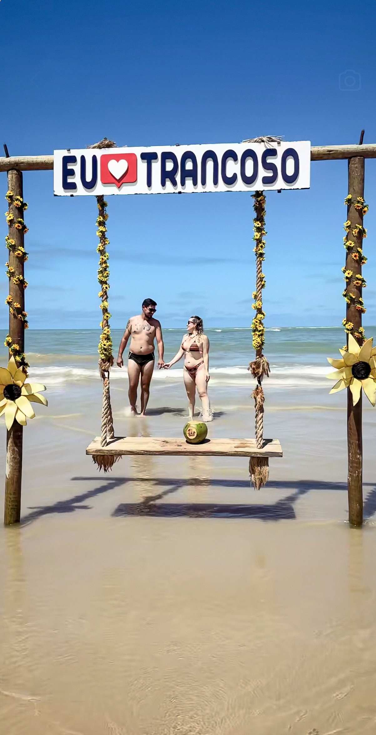 Casal passeando sob o balanço Eu amo Trancoso